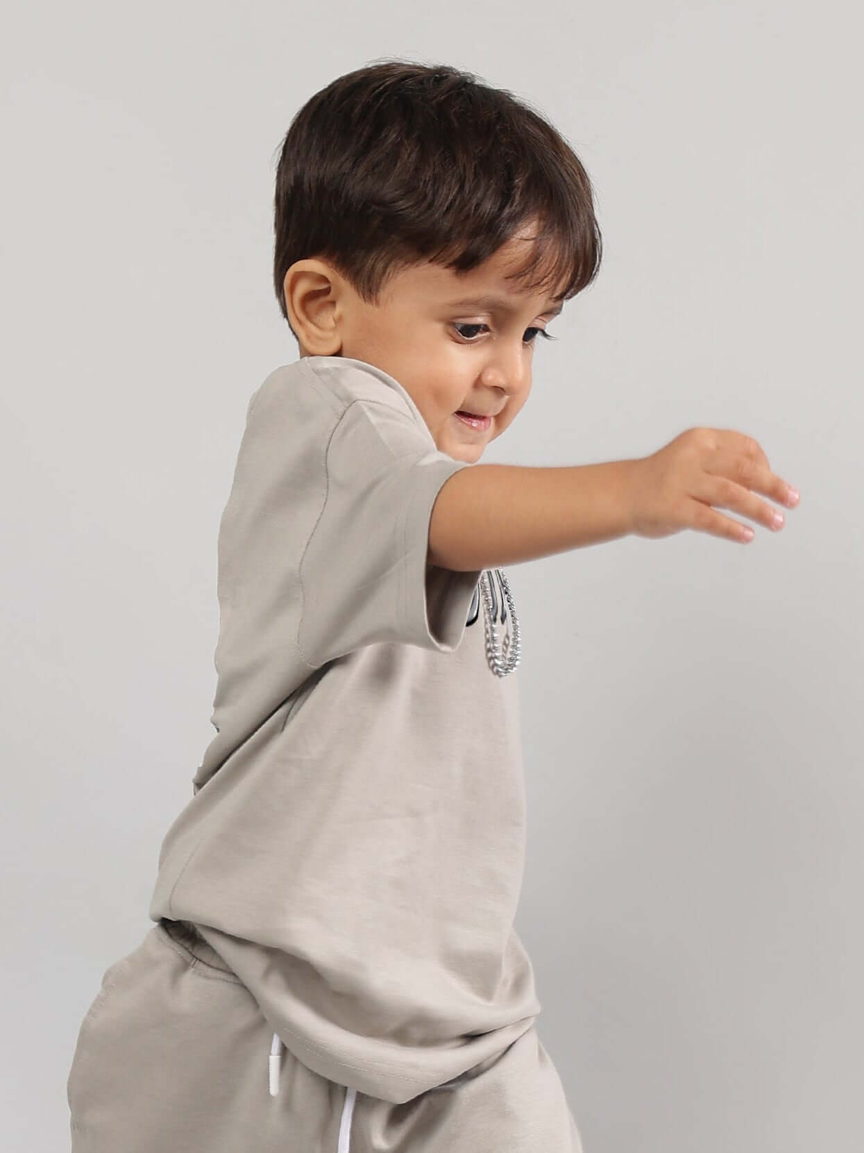 Child wearing a grey Positive Rabbit T-shirt, made to order by DUDS, smiling and playing, suitable for boys and girls.