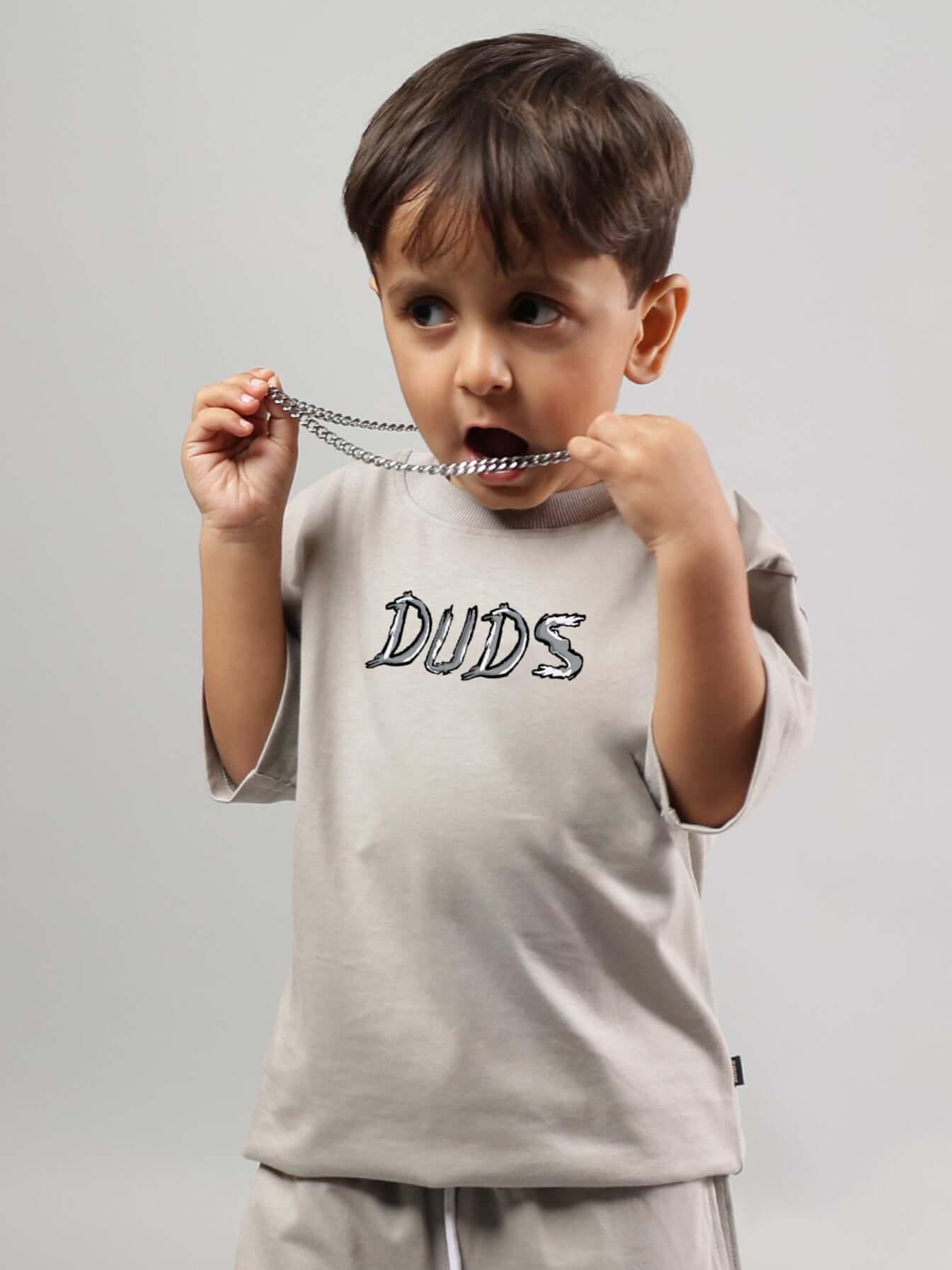 Young boy wearing a grey Positive Rabbit T-shirt, featuring DUDS logo, playful expression, perfect for boys and girls, custom fit available.