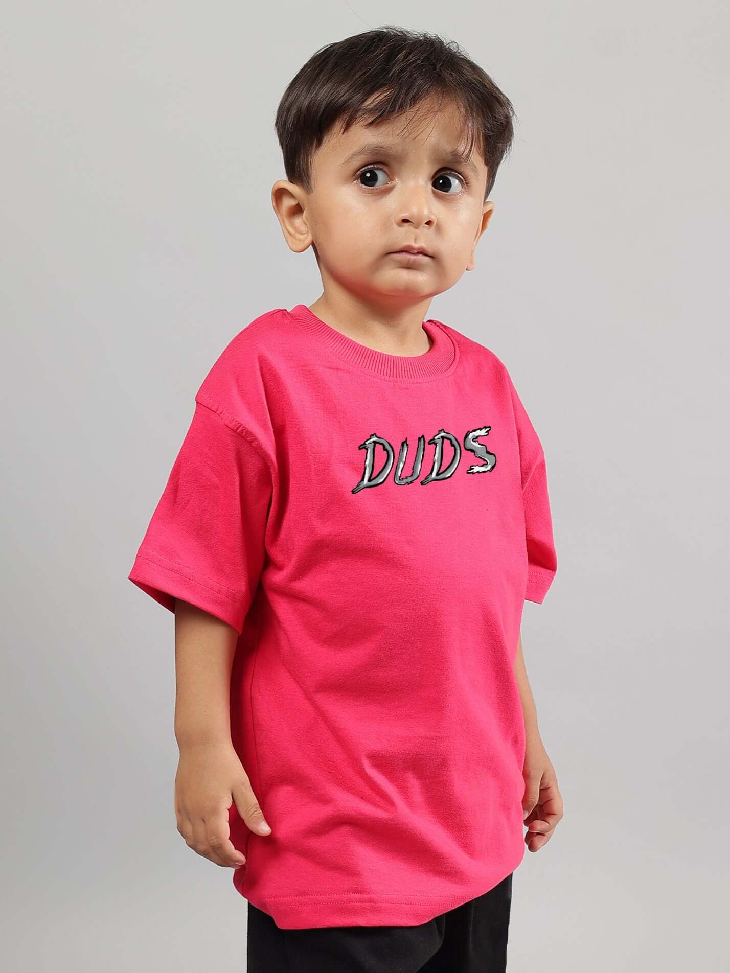 Young child wearing a pink Positive Rabbit T-shirt for boys and girls by DUDS, showcasing casual style.