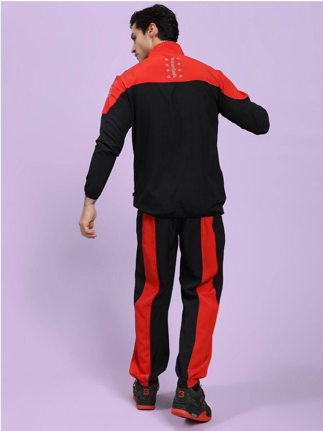 POWER BLOCK CO-ORD SET BLACK RED Person wearing a black and red tracksuit on a light purple background