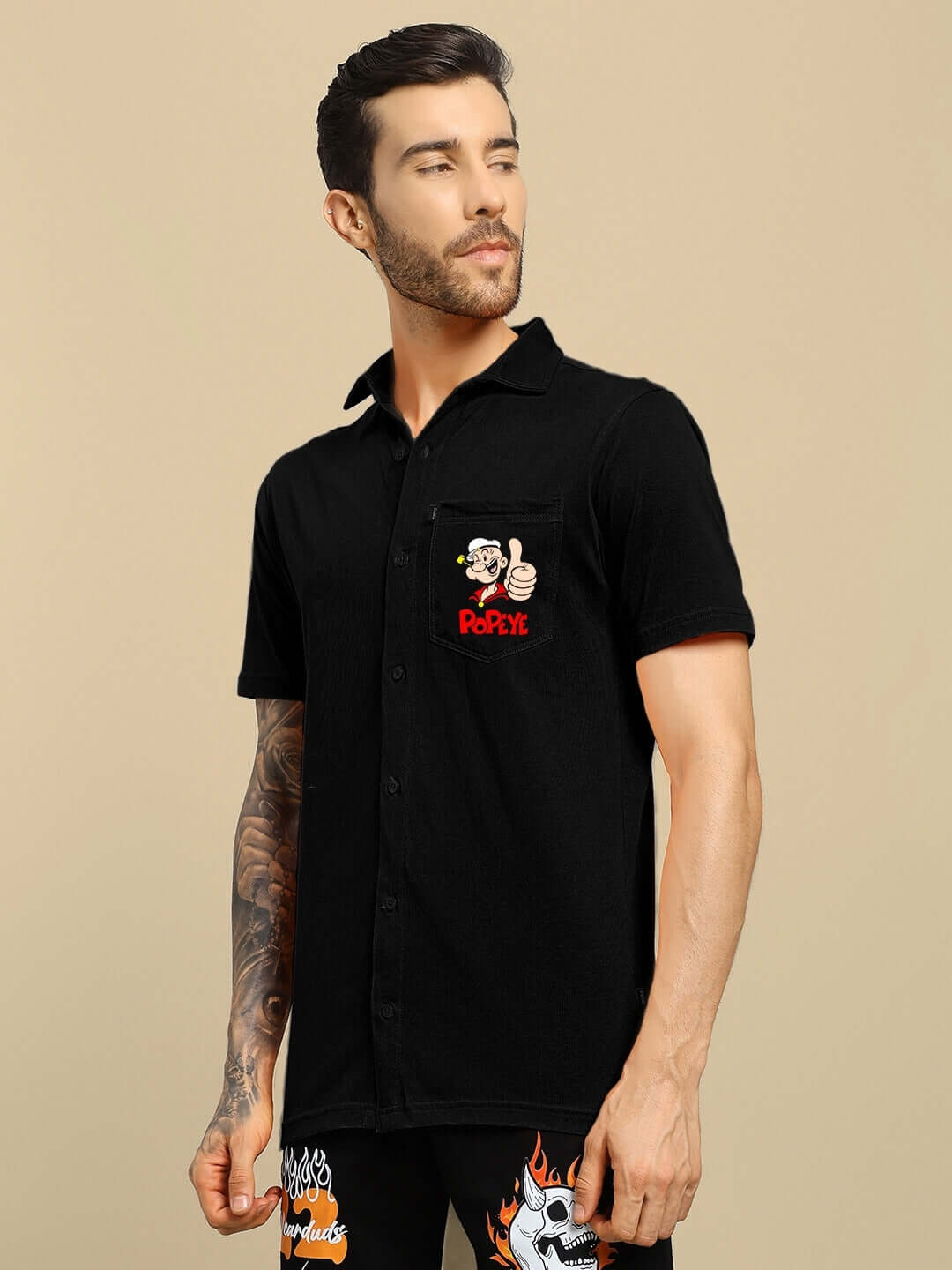 Model wearing black Power Men Popeye printed shirt with short sleeves and a front pocket featuring Popeye graphic.