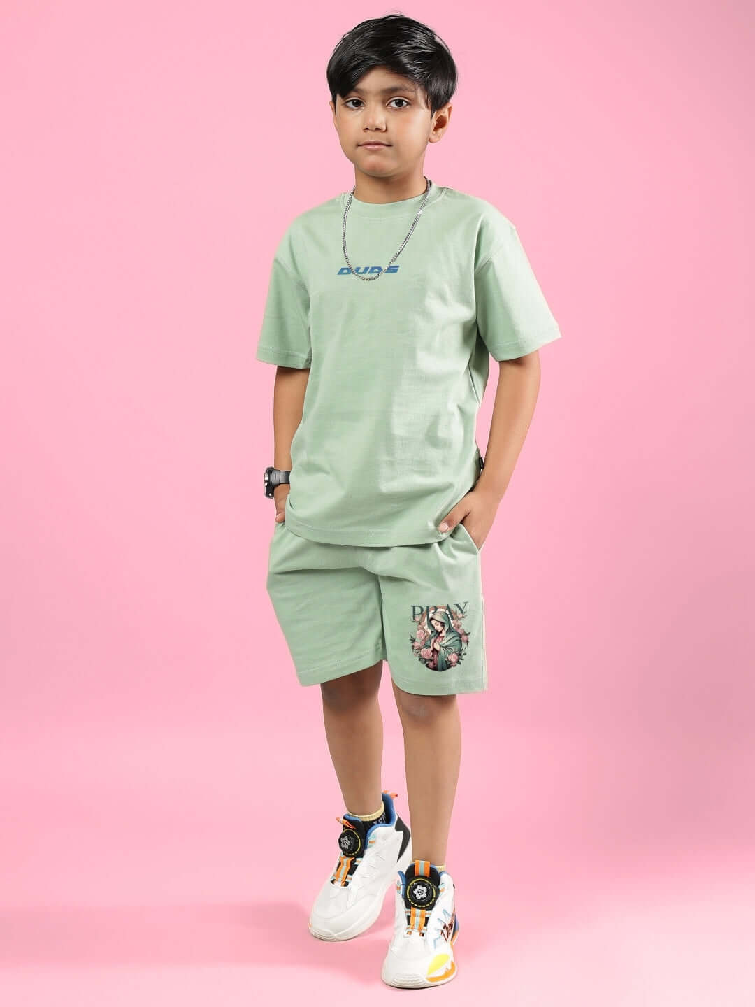 Boy wearing PRAY & PEACE CO-ORD FOR BOYS & GIRLS NYANZA GREEN in a studio, showcasing custom fitted casual wear with a pink backdrop.