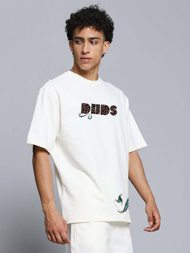 Model wearing off-white oversized t-shirt with fish print, made from premium heavy gauge fabric, 97% cotton, 3% elastane. Designed in India.