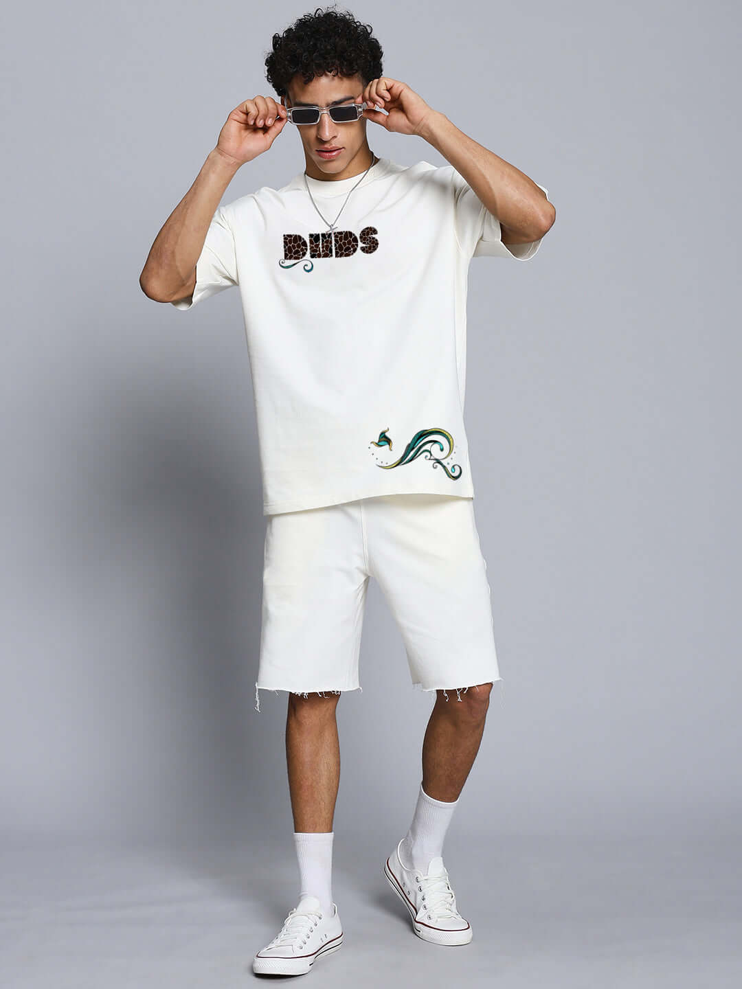 Person wearing oversized off-white T-shirt with fish print and sunglasses, casual streetwear fashion style.