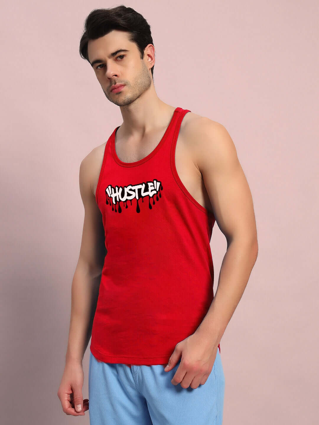 Man wearing PRIMITIVE HUSTLE GYM T-SHIRT RED, perfect for workouts and embodying raw energy. Features "Hustle" slogan in bold style.