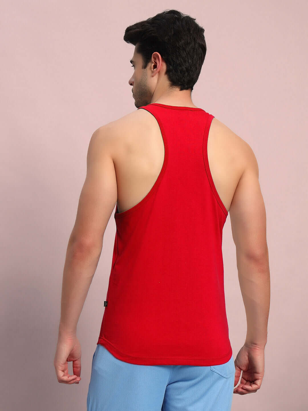 Man wearing PRIMITIVE HUSTLE GYM T-SHIRT RED shows athletic back in workout setting.