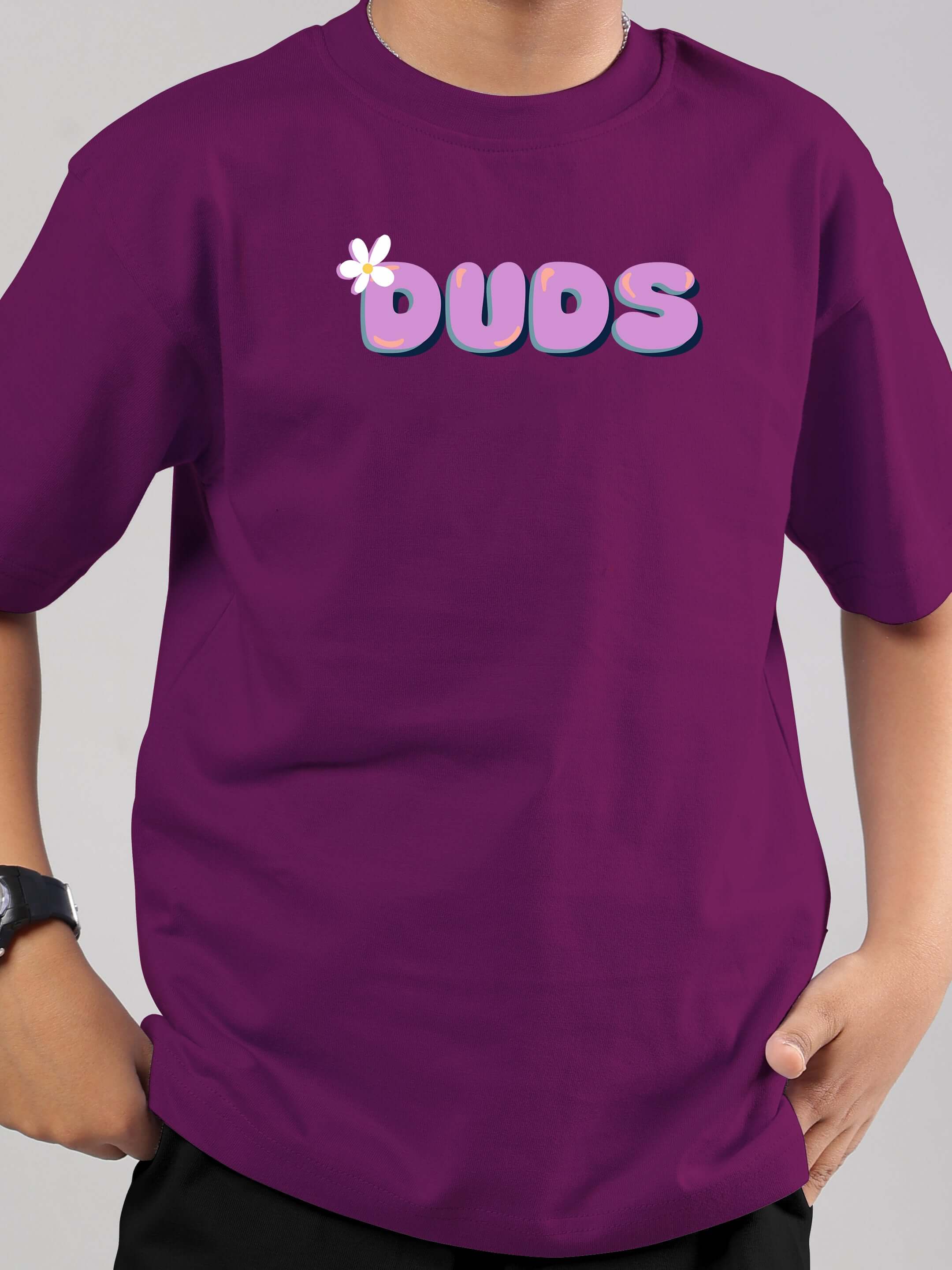 Purple DUDS t-shirt worn by a child, featuring bold lettering on the front. Suitable for boys and girls; part of a made-to-order fashion line.