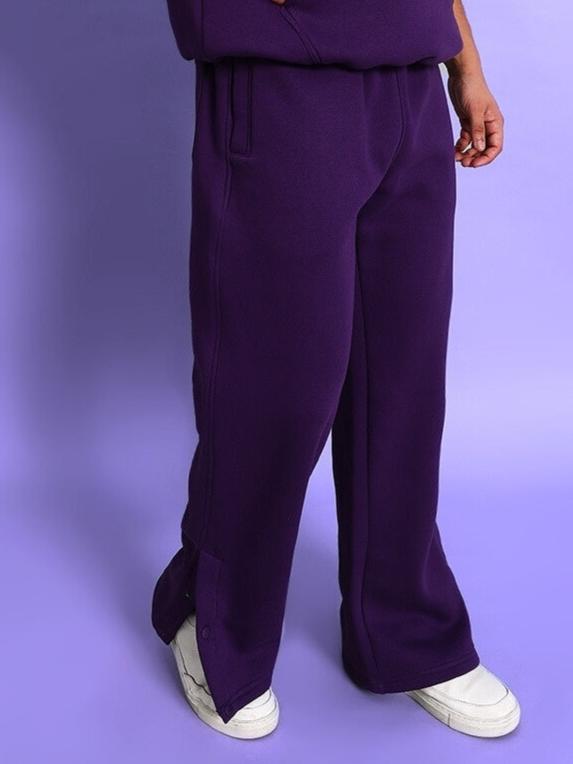Person wearing SOOTY COTTON FLEECE PANT PURPLE for casual streetwear style, showing elasticated waistband and ribbed cuffs.