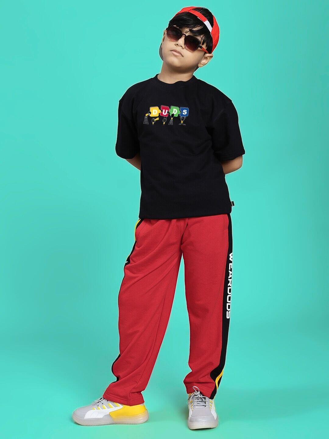 Child wearing a PUZZEL T-SHIRT FOR BOYS AND GIRLS BLACK standing confidently against a turquoise background.