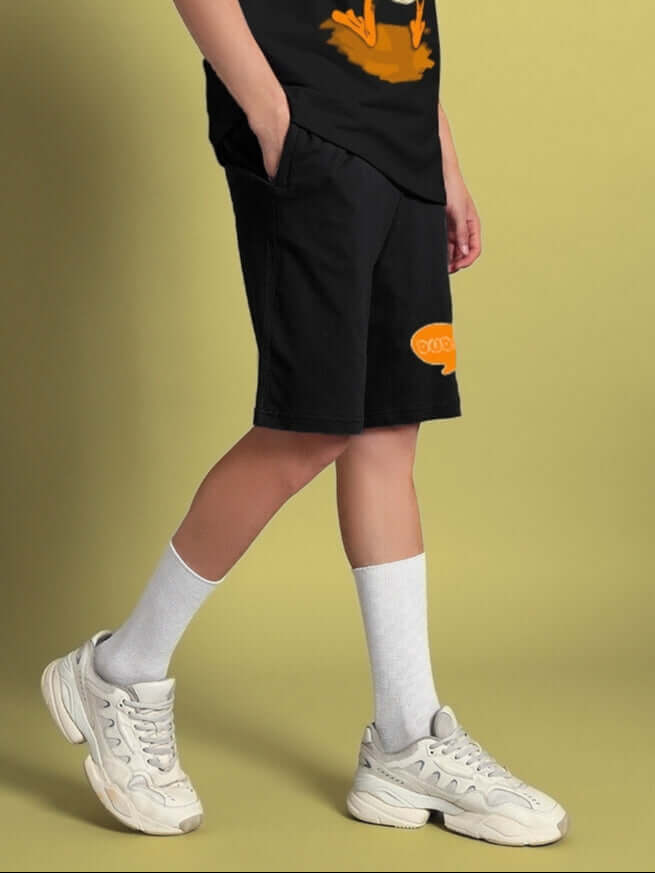 Person wearing QUACK OFF SUMMER COTTON SHORTS BLACK, showcasing casual streetwear style with playful graphic design.