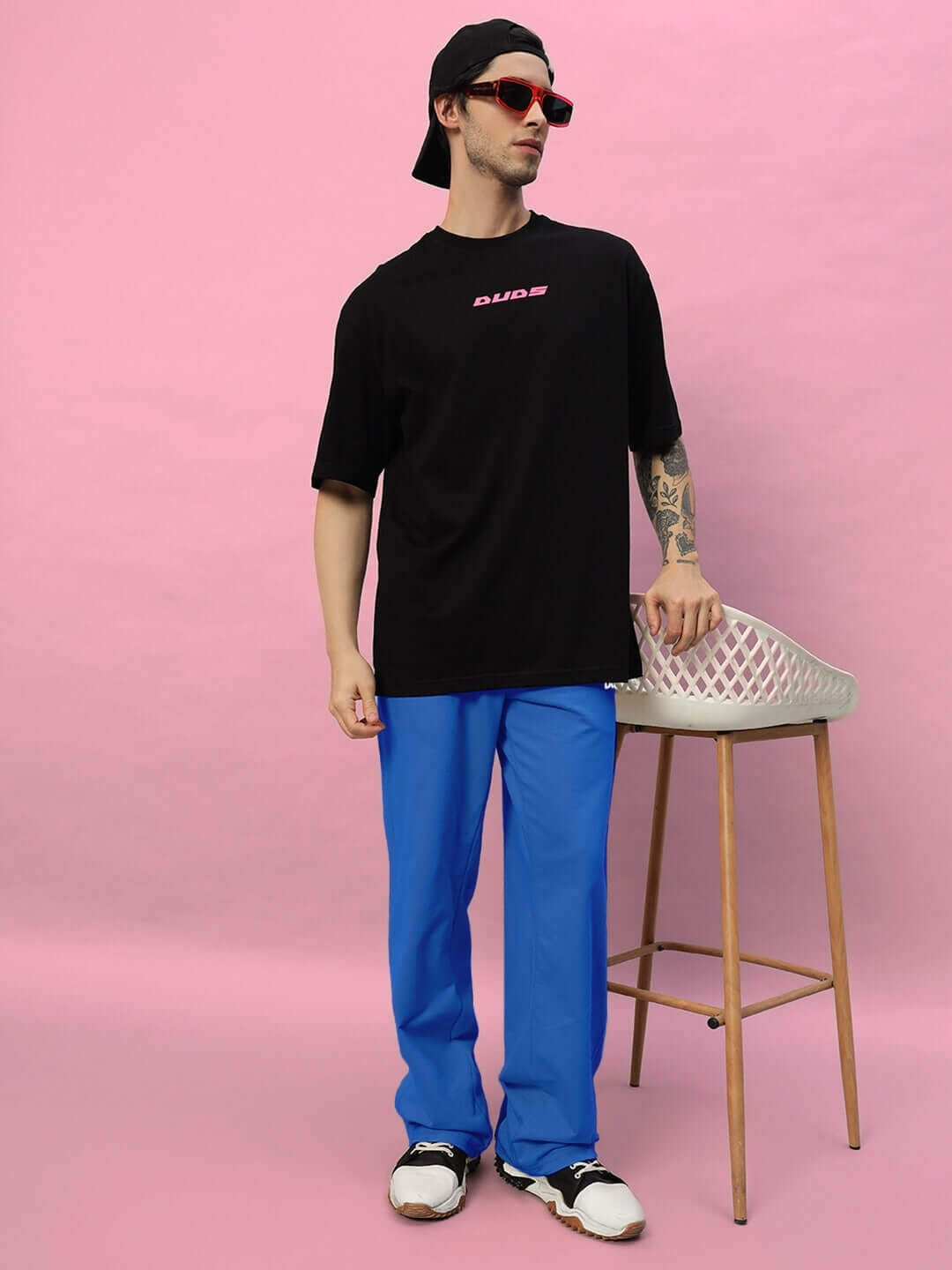 Man wearing Quantum Relaxed-Fit Joggers in R Blue with DUDS shirt and accessories against a pink backdrop.