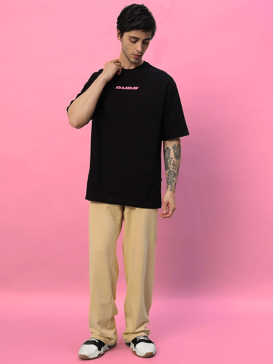 Man wearing Quantum Relaxed-Fit Joggers in Beige and black t-shirt against a pink background.