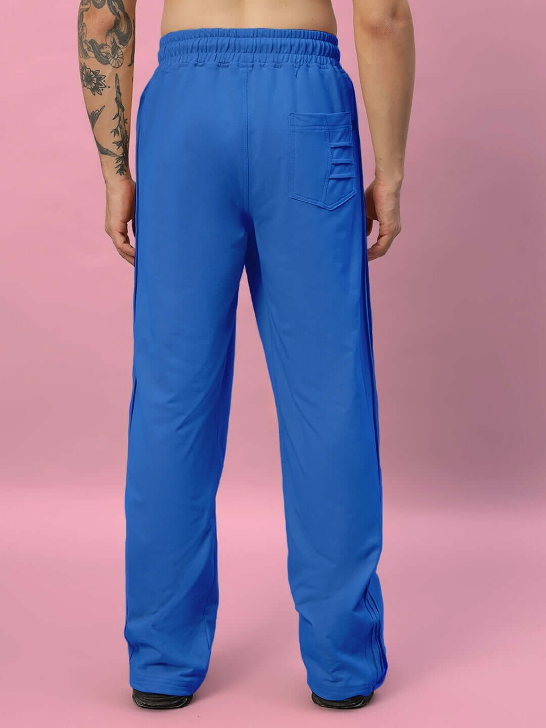 Person wearing blue relaxed-fit joggers with rear pocket against pink background