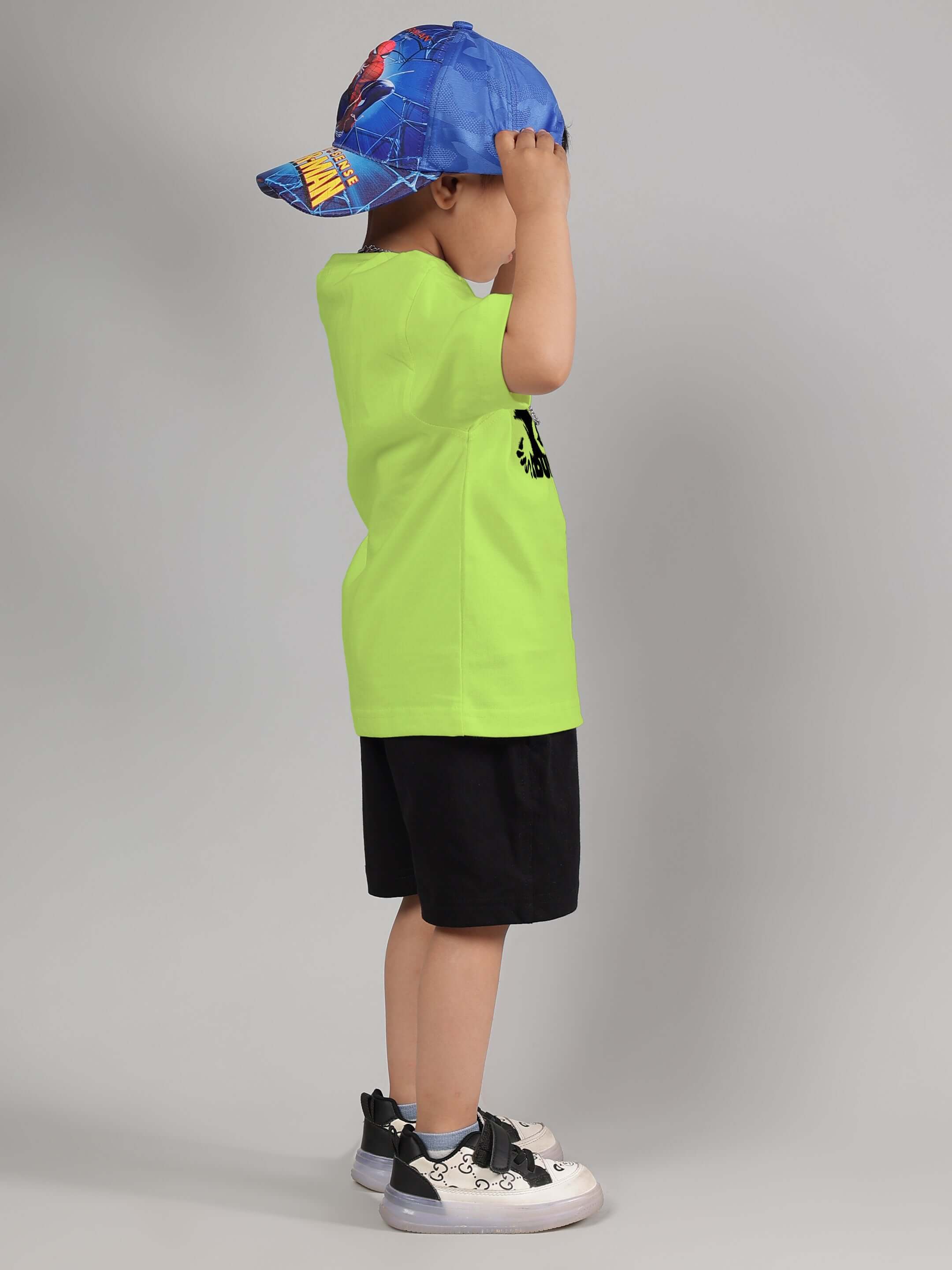 Child wearing neon green raccoon t-shirt and blue cap, side view.