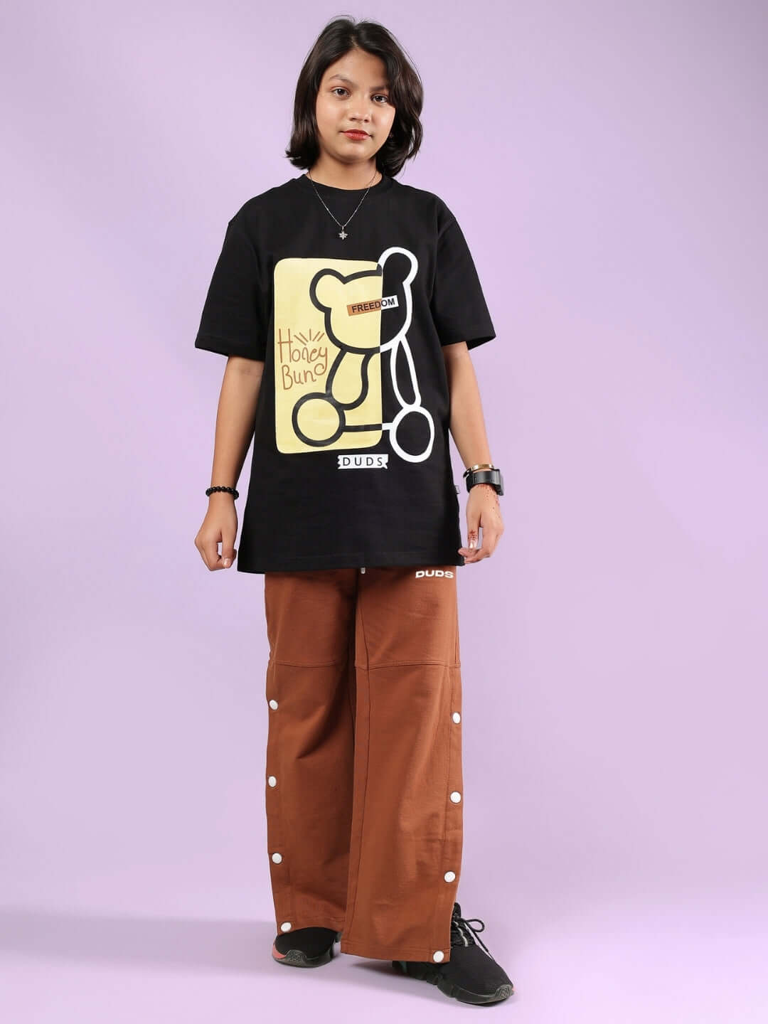 Child wearing brown RACER JOGGER FOR BOYS & GIRLS BROWN with black graphic t-shirt, showcasing made-to-order fashion by experienced tailors.