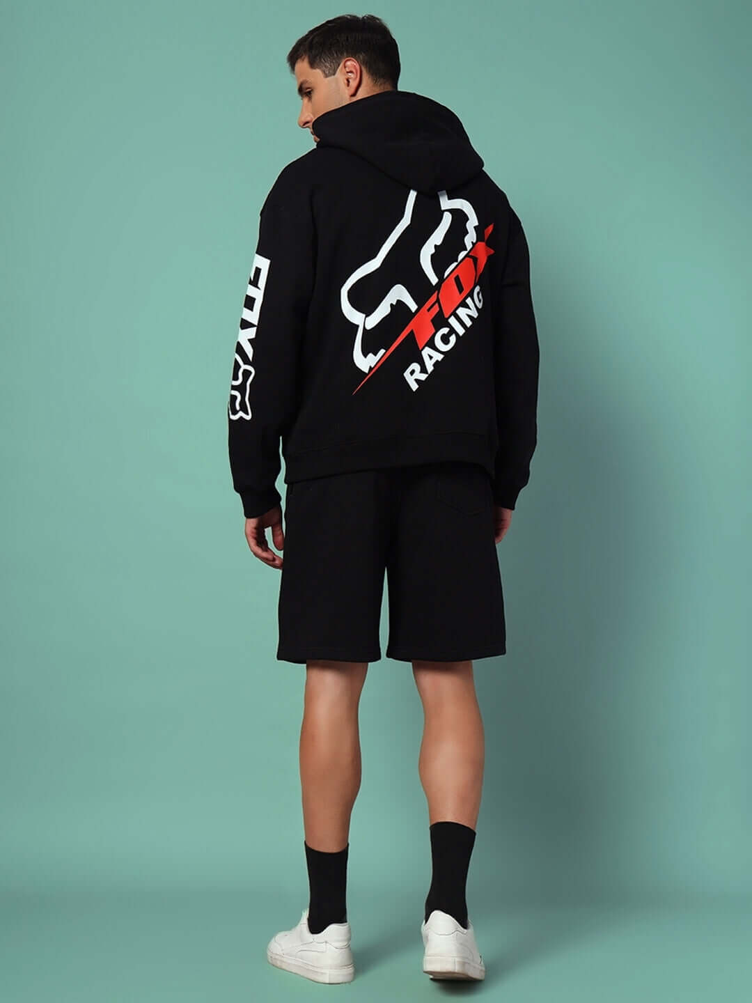 Back view of a person wearing the RACING FOX COTTON FLEECE CO-ORD BLACK with racing-inspired graphics on a teal background.