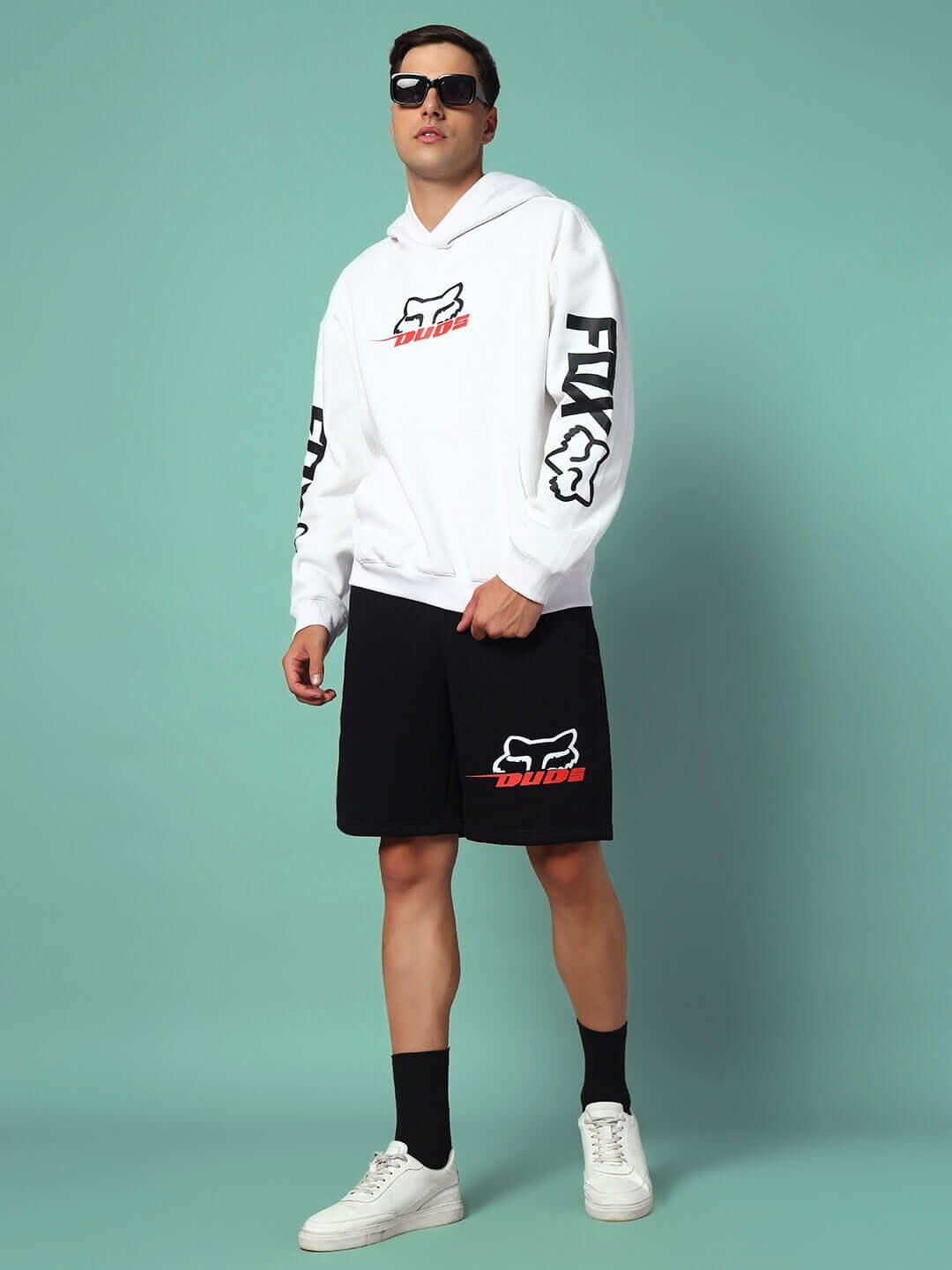 Man wearing RACING FOX FLEECE CO-ORD WHITE BLACK with sunglasses, showcasing a stylish streetwear look in a teal background.