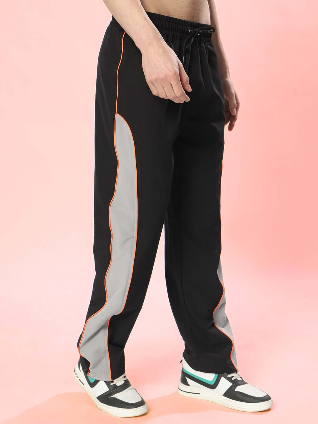Model wearing black-grey relaxed fit cargo pants with orange trim, featuring side pockets, customized fit option available, by DUDS.
