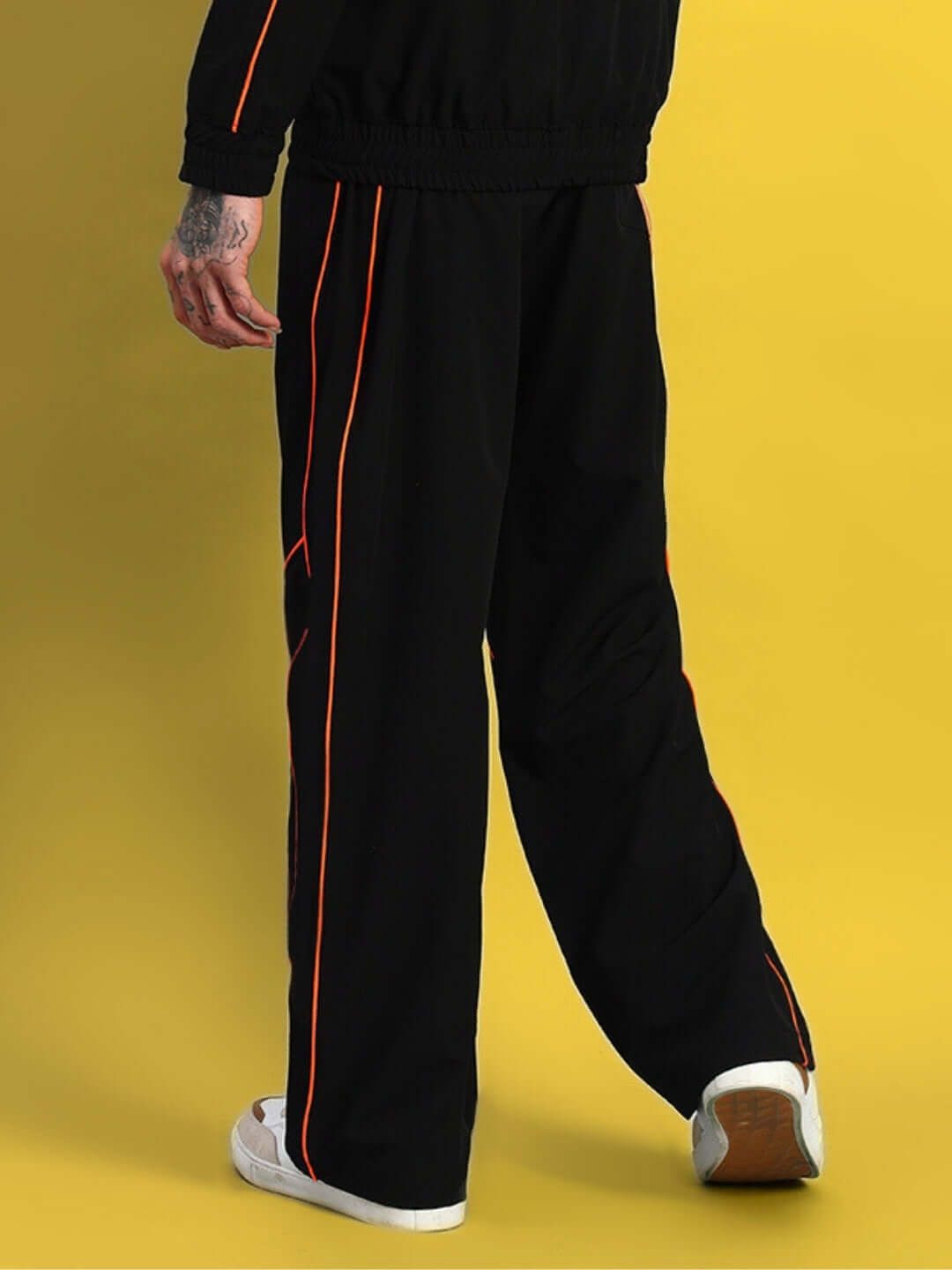 Model wearing RAIDER RELAXED PANT JOGGER in black with orange accents, tailored by DUDS, featuring a custom fit option.