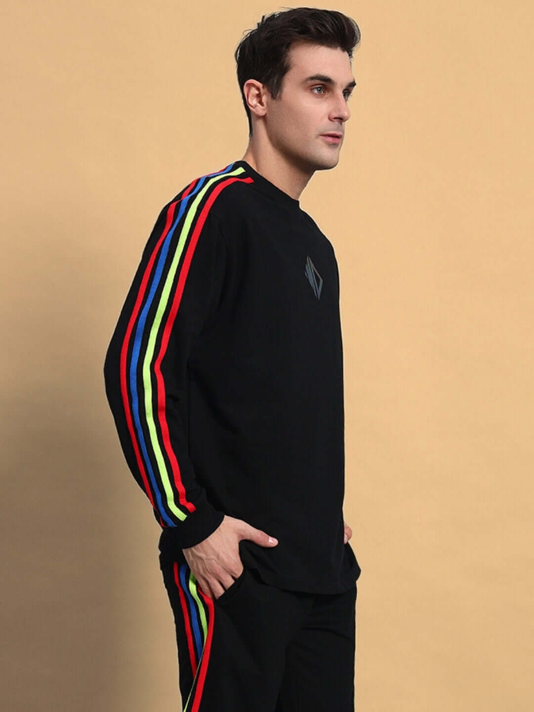 Rainbow colorblock sweatshirt in black with vibrant stripes on sleeves, made-to-order by DUDS, worn by a model on a beige backdrop.