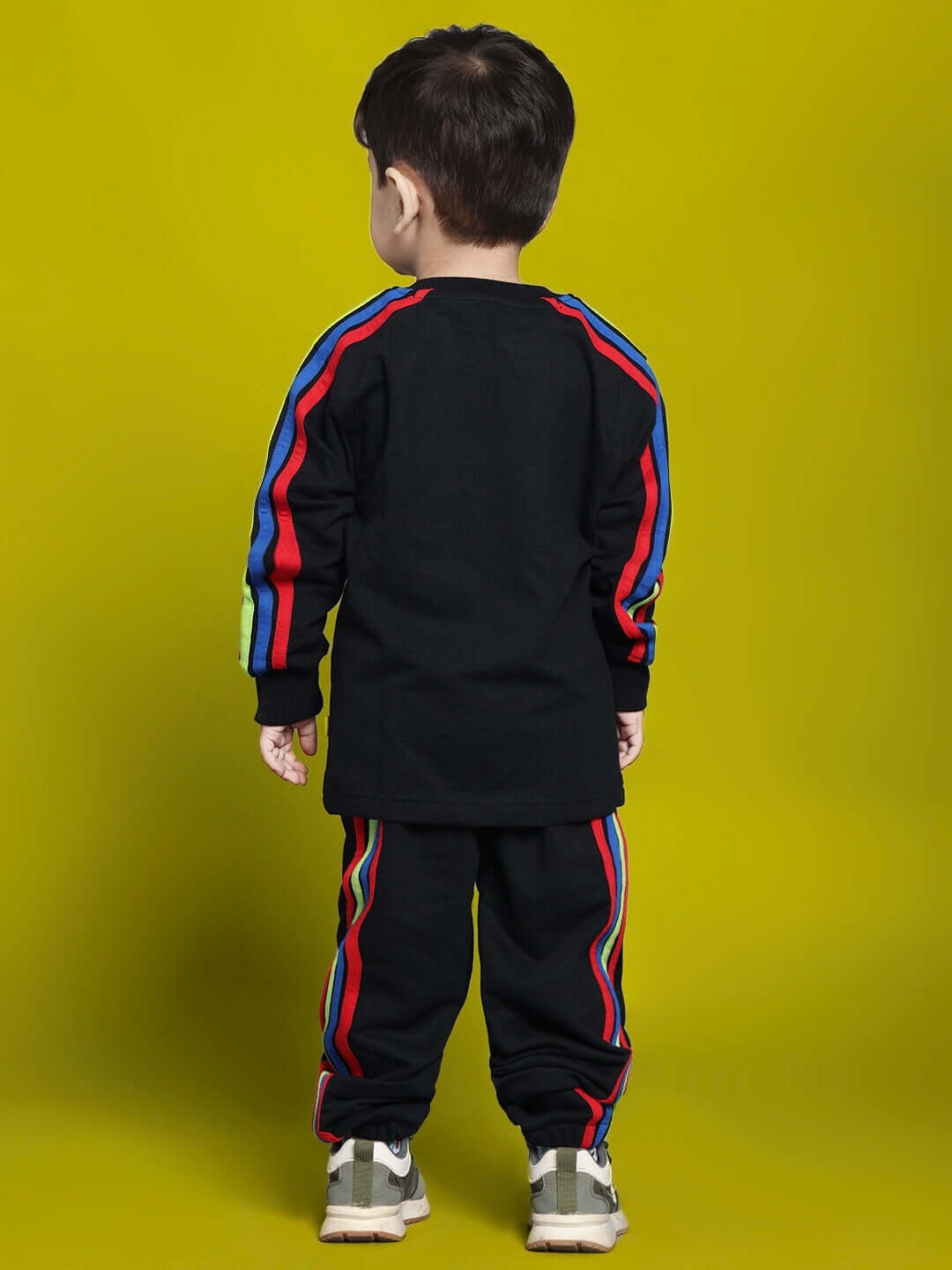 Child wearing black rainbow co-ord outfit for boys and girls, featuring colorful stripes on sleeves and pants, made by DUDS.