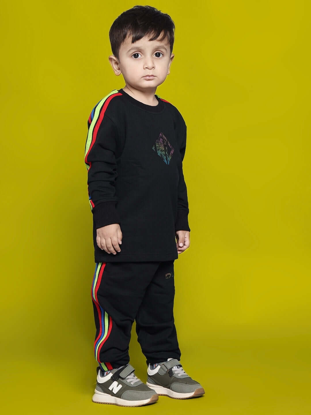 Child wearing black rainbow co-ord set for boys and girls, featuring colorful side stripes. Made to order by DUDS, tailor custom fit available.