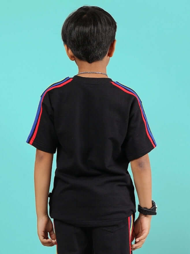 Boy wearing a RAINBOW OVERSIZED T-SHIRT FOR BOYS & GIRLS BLACK with colorful shoulder stripes, back view.
