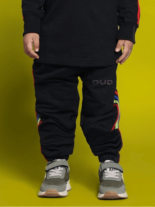Child wearing black rainbow jogger pants, designed for active boys and girls, by DUDS. Made-to-order with customizable sizing options.