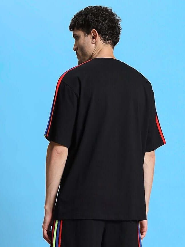 Back view of model wearing RAINBOW OVER-SIZED T-SHIRT BLACK with colorful stripe detail, made of Premium Heavy Gauge Fabric.
