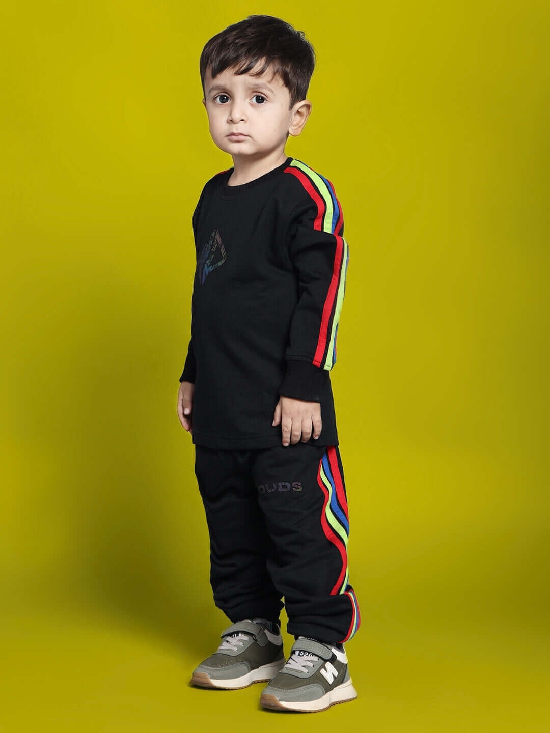 Young child wearing a black rainbow co-ord set for boys and girls from DUDS, featuring colorful stripes on sleeves and pants. Made to order.