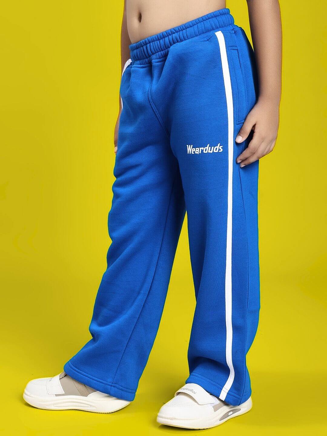 Child wearing RAPID STRIDE FLEECE CO-ORD FOR BOYS AND GIRLS ROYAL BLUE joggers with white stripe, side view.
