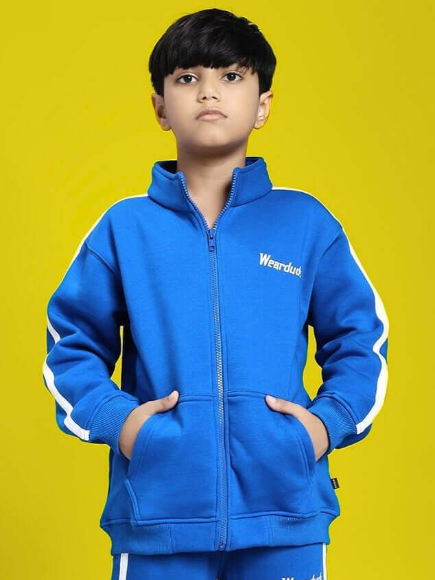 Boy wearing RAPID STRIDE FLEECE JACKET FOR BOYS AND GIRLS ROYAL BLUE in a sporty, casual style against a yellow background.