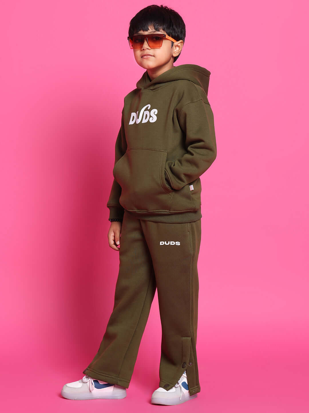 Child wearing rare edition olive green fleece pants and hoodie on pink background