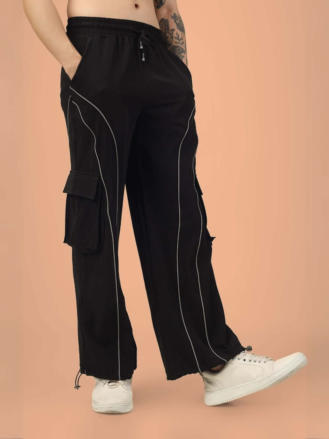 Black Ray Reflector Parachute Cargo Pants with Custom Fit Option, side view, against a peach background.