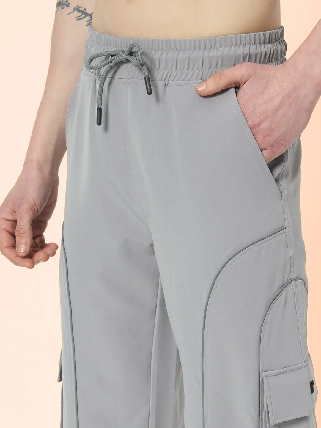Close-up of grey Ray Reflector Parachute Cargo Pants with pockets and drawstring waist, customizable size option available.