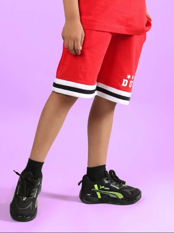 Kid wearing DIGGIN SHORTS FOR BOYS & GIRLS RED against purple background