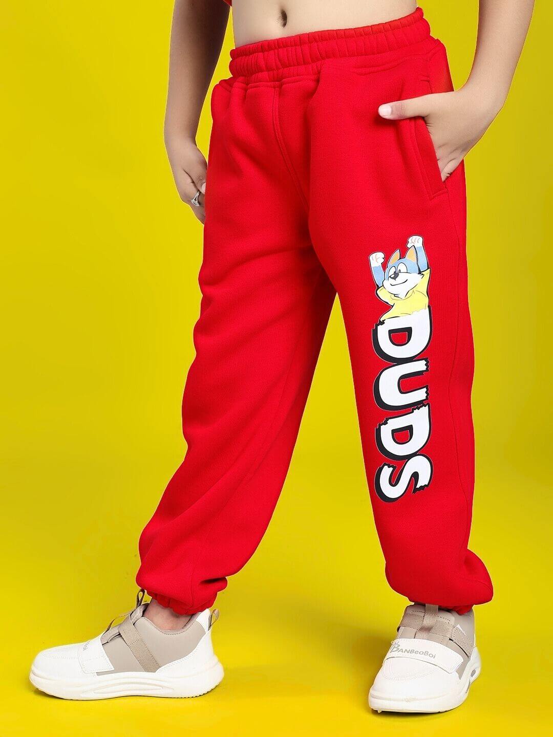 Child wearing HUG WITH THE DOG FLEECE CO-ORD FOR BOYS AND GIRLS RED with fun dog graphic, showcasing cozy and stylish red pants for kids.