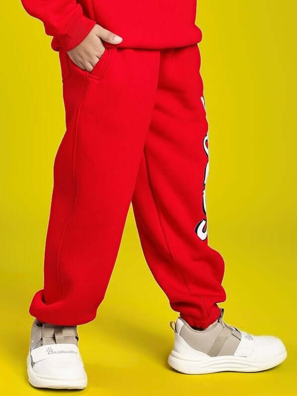 Child wearing HUG WITH THE DOG FLEECE JOGGER FOR BOYS AND GIRLS RED, showcasing bold red color and playful design.