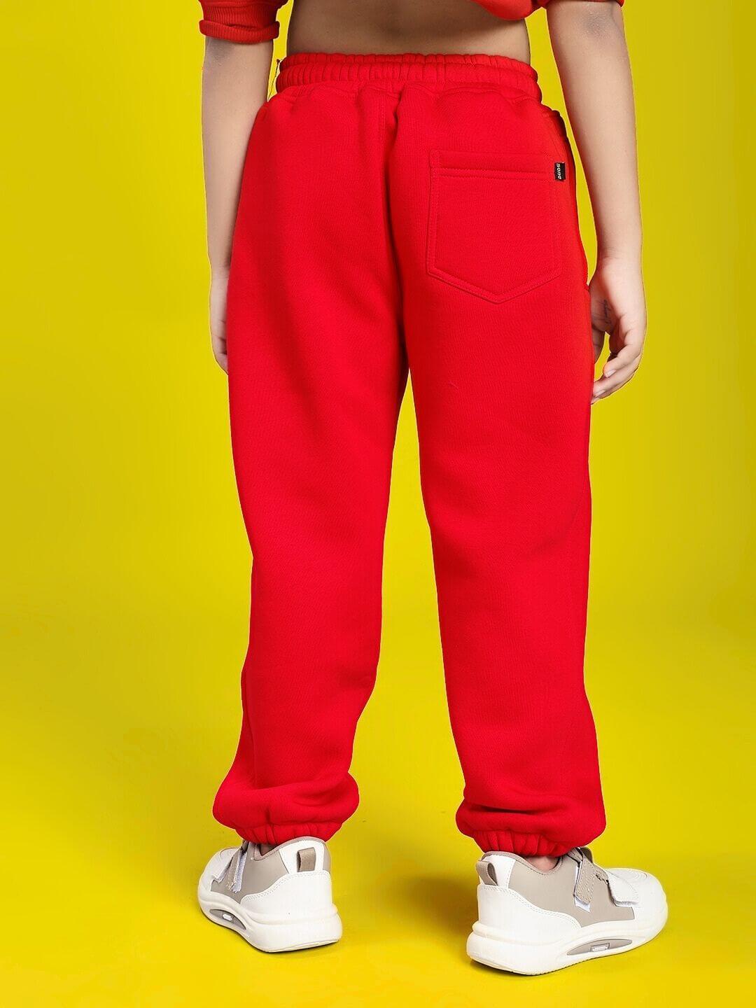 Child wearing HUG WITH THE DOG FLEECE JOGGER FOR BOYS AND GIRLS RED, showcasing red joggers with elastic waistband and cuffs.