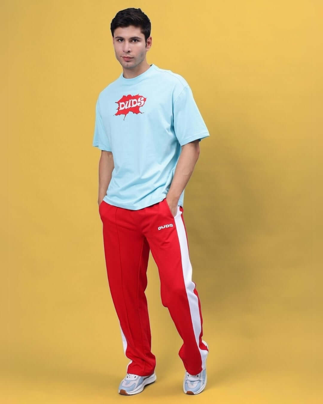 Model wearing DUDS red side seam plated joggers, paired with a blue t-shirt, showcasing stylish casual fashion.