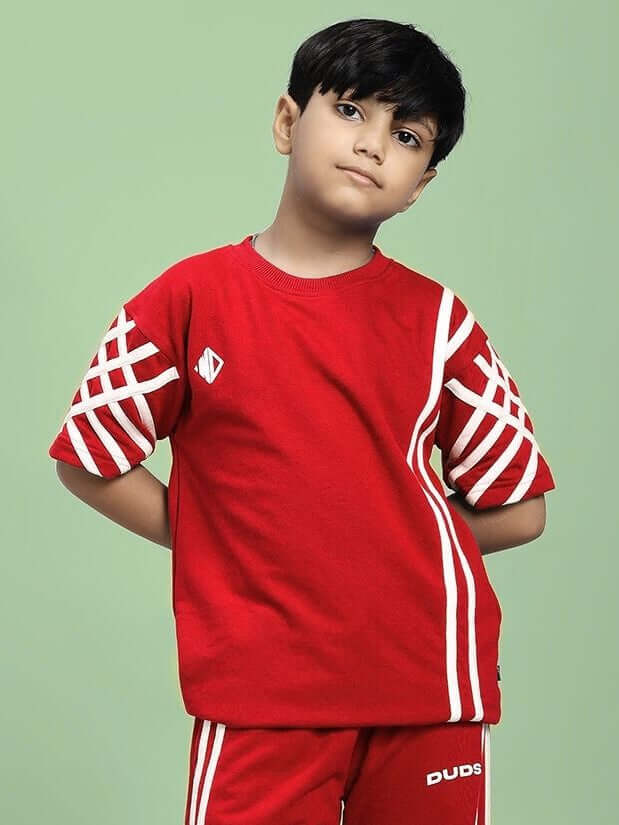 Young boy wearing UNITED STRIPE T-SHIRT FOR BOYS AND GIRLS RED against green background.