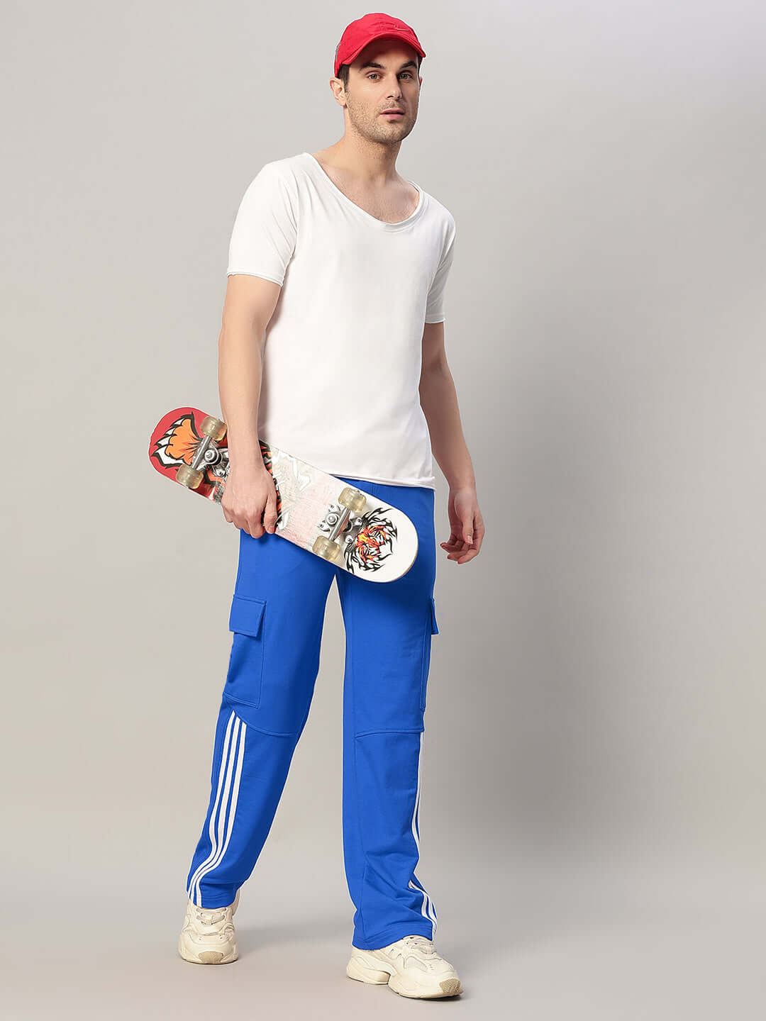 Man posing in REDROIT R Blue relaxed fit joggers, holding a skateboard, highlighting sporty casual style.