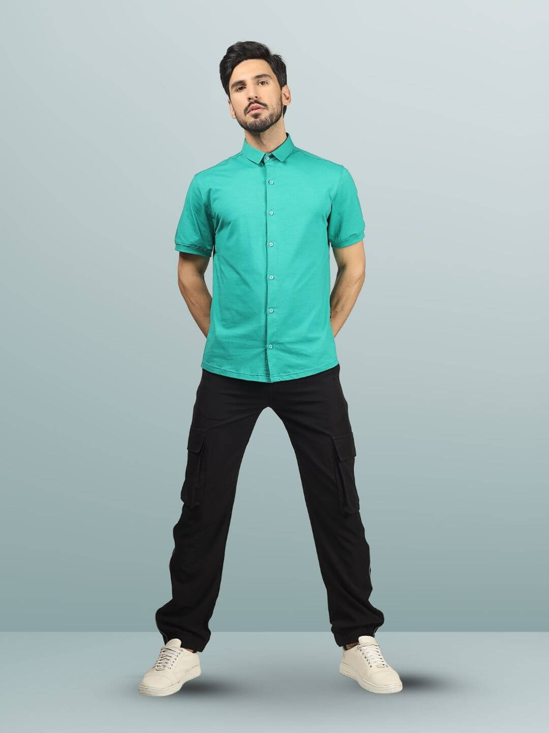 Man wearing Reflector Cargo Pants 2.0 in black, paired with a teal shirt and white sneakers, highlighting stylish and customizable fit.