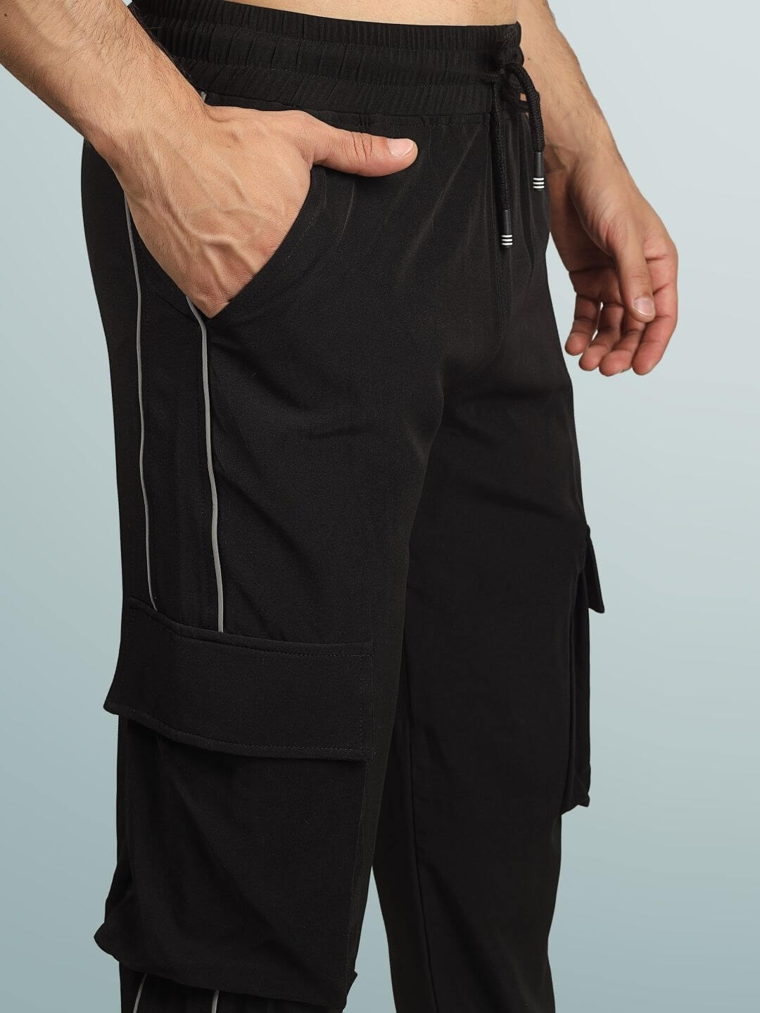 Man wearing REFLECTOR CARGO PANTS 2.0 BLACK with reflective details and pockets, showcasing urban street style and comfort.