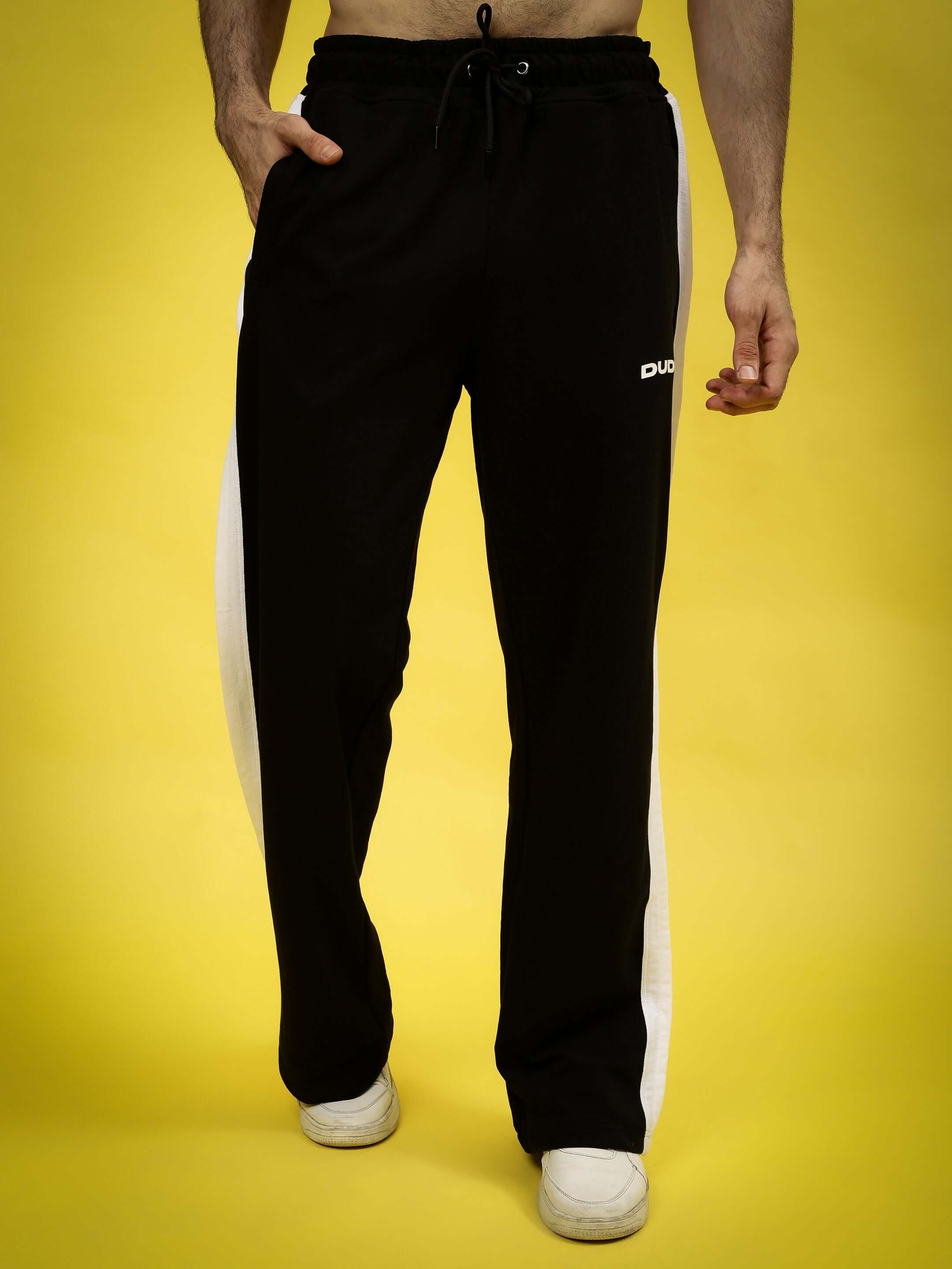 Model wearing REGAL BAGGY JOGGERS in black and white with drawstring waist and side stripe, perfect for a custom fit from DUDS.