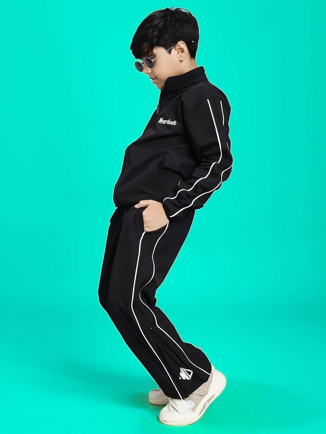 Young model wearing RELIGHT RELAXED FIT JACKET FOR BOYS AND GIRLS BLACK against a turquoise background.