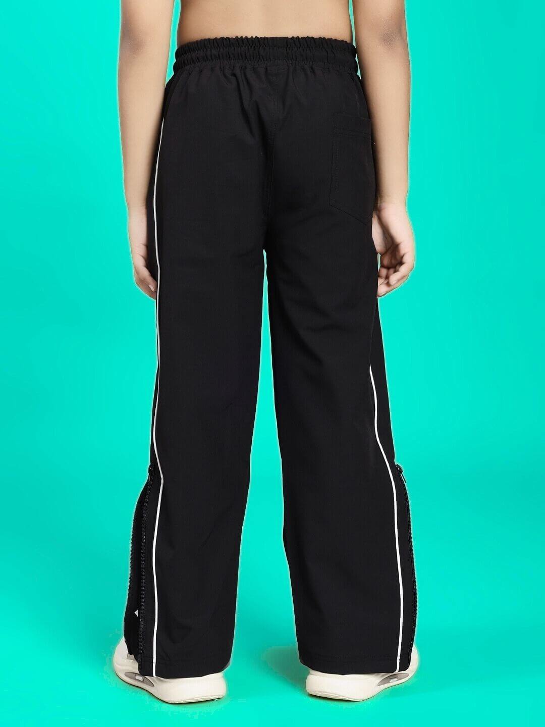 Child wearing RELIGHT RELAXED FIT JOGGER FOR BOYS AND GIRLS BLACK with side stripes, against a turquoise background.