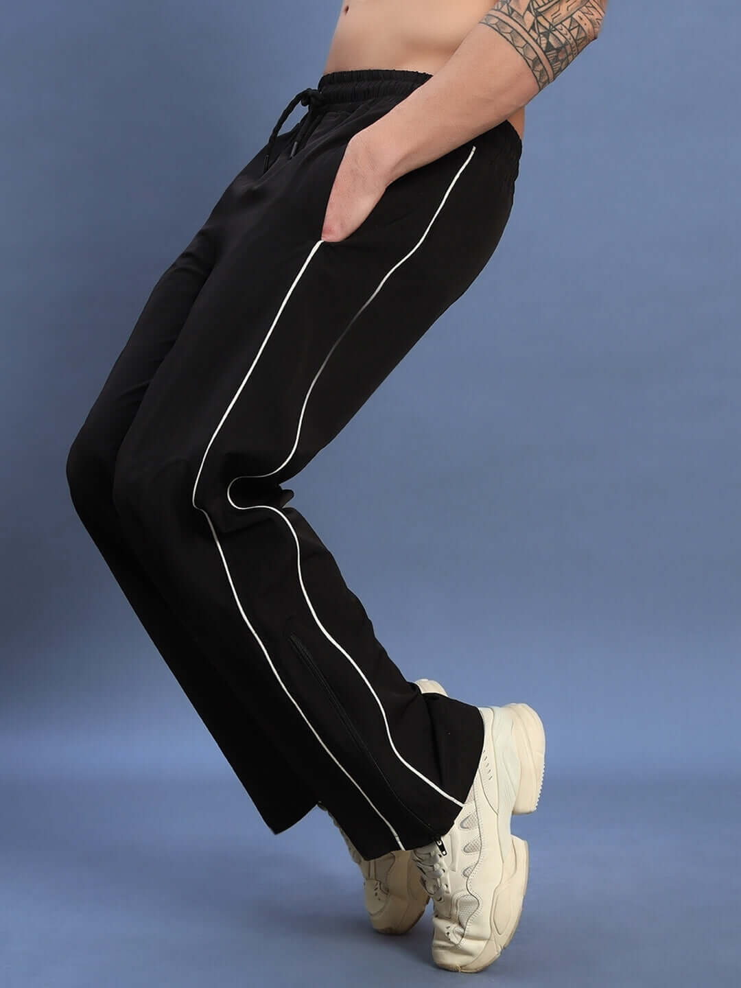 Man wearing RELIGHT relaxed-fit black joggers with white stripes, showcasing comfortable and stylish design, perfect for custom fit.