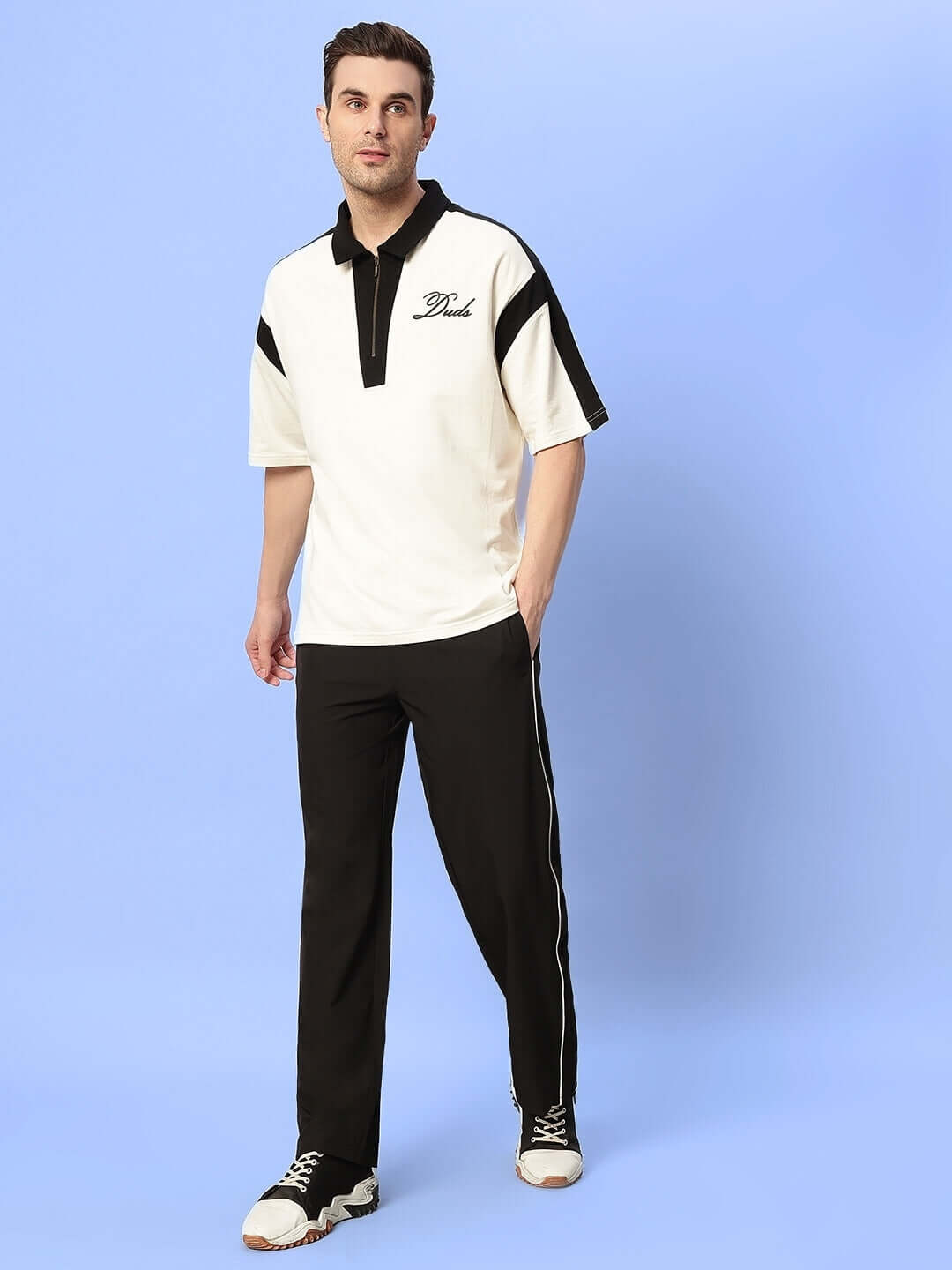 Model wearing relaxed-fit joggers in black with white sneakers and a matching top, showcasing style and comfort for everyday wear.