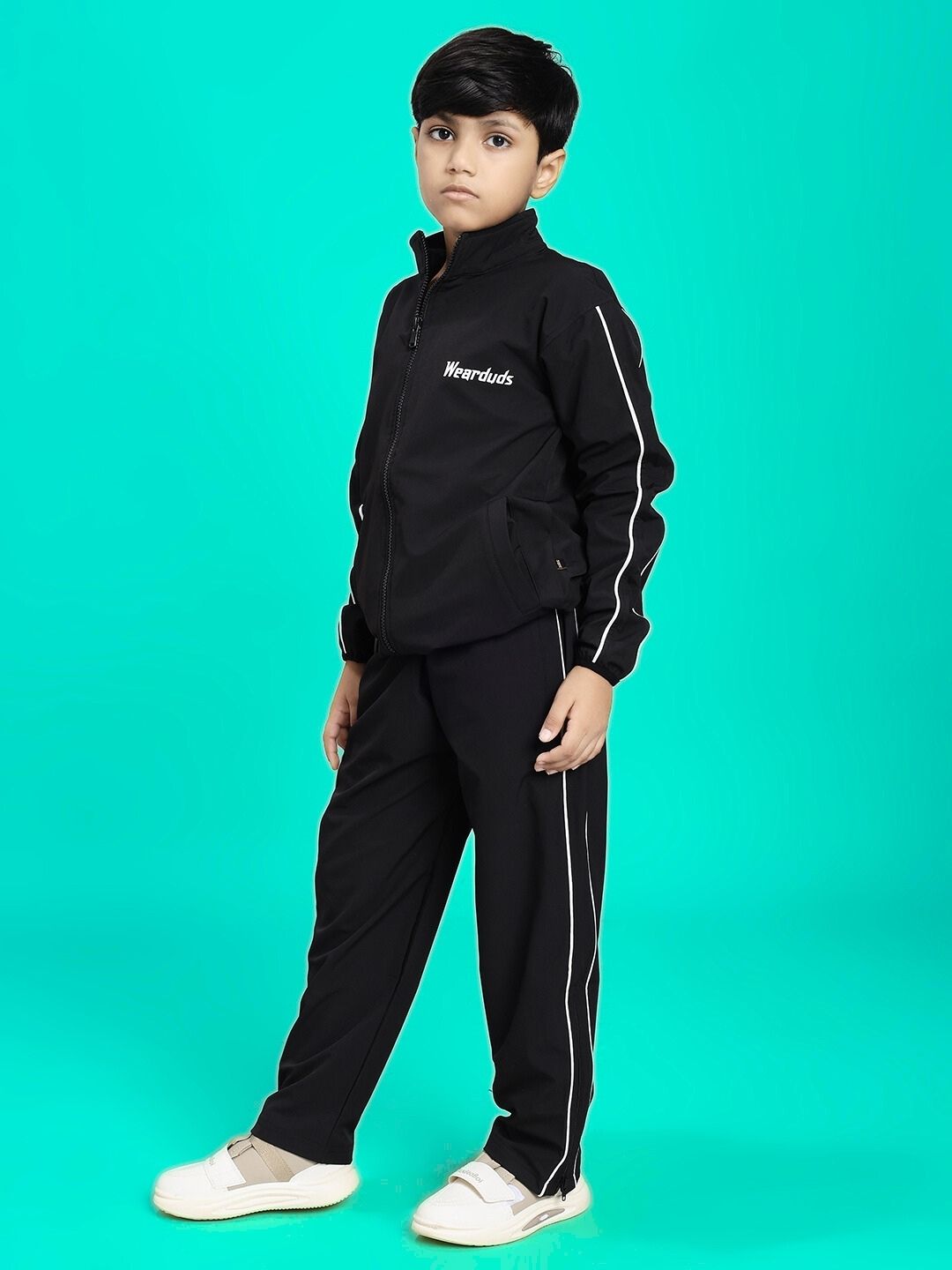Boy wearing RELIGHT RELAXED FIT CO-ORD SET FOR BOYS AND GIRLS BLACK against green background